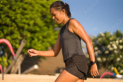 Fototapeta Naklejka Na Ścianę i Meble -  portrait of young attractive and sweaty happy Asian Indonesian woman in her 40s smiling satisfied after hard beach running workout in sports training and healthy lifestyle concept