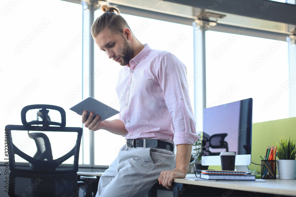 Young modern business man working using digital tablet while sitting in the office. Young modern business man working using digital tablet while sitting in the office.