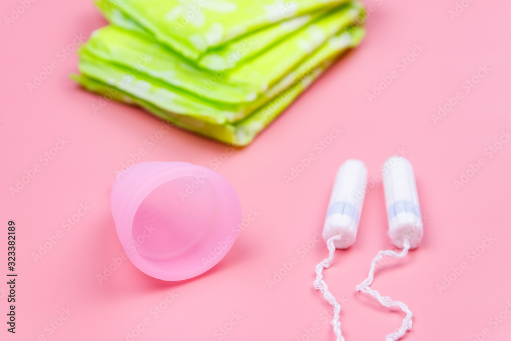 Sanitary pad, tampons and menstrual cup on pink background. Concept of critical days, menstruation, feminine hygiene Sanitary pad, tampons and menstrual cup on pink background. Concept of critical days, menstruation, feminine hygiene