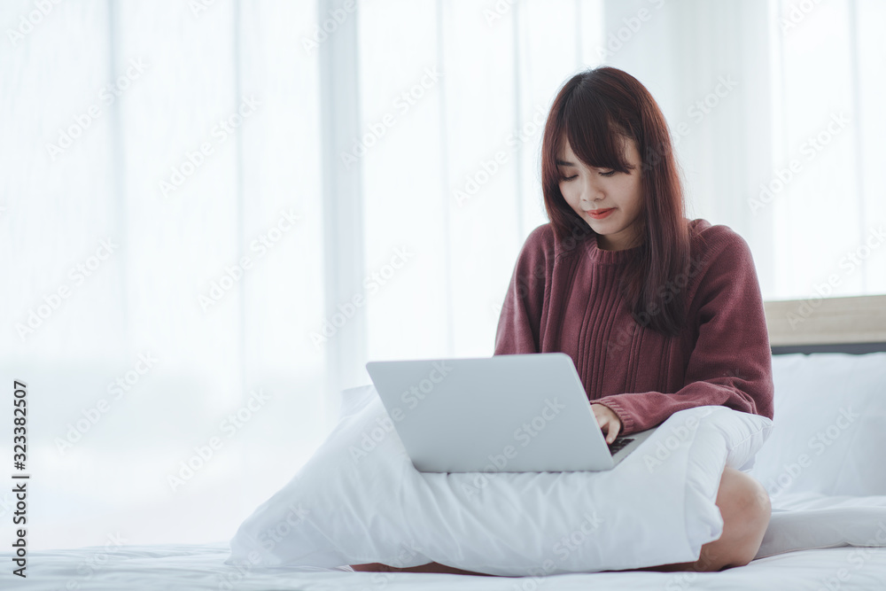 woman working on a laptop sitting on the bed in the house. woman working on a laptop sitting on the bed in the house.
