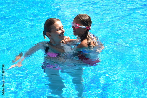 Mother and daughter having fun by the pool. Happy parenthood. The mother and daughter at a hotel in the tropics