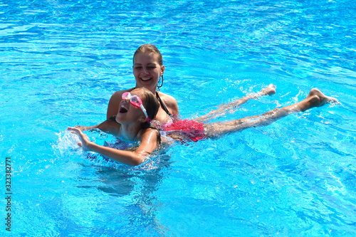 Mother and daughter having fun by the pool. Happy parenthood. The mother and daughter at a hotel in the tropics