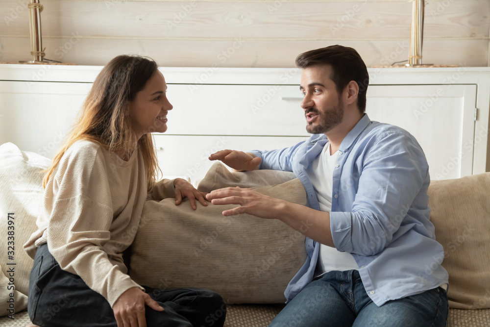 Happy millennial couple talk relaxing in living room Happy millennial couple talk relaxing in living room