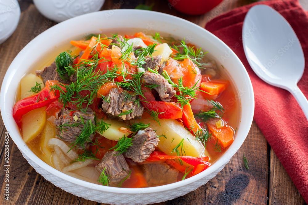 Khashlama with beef and vegetables on a wooden table, selective focus