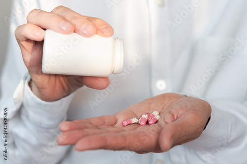 Female hand close up holding a medicine, elderly woman hands with pill on spilling pills out of bottle .