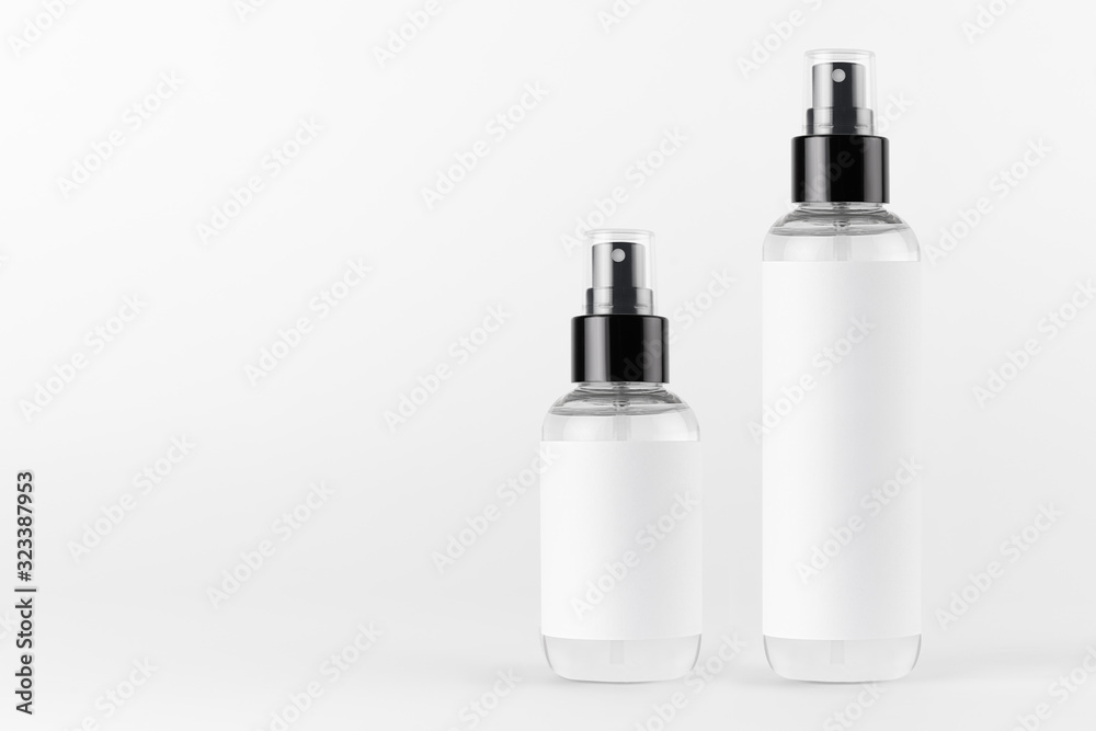 Tall, low transparent spray dispenser bottle for cosmetics with white label on white background, mock up for branding, presentation, design. Tall, low transparent spray dispenser bottle for cosmetics with white label on white background, mock up for branding, presentation, design.