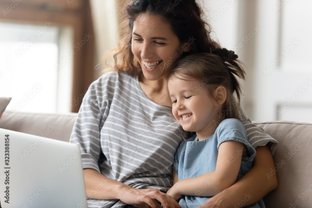 Happy young mother watching funny cartoons on computer with daughter. Happy young mother watching funny cartoons on computer with daughter.