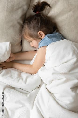 Happy peaceful little kid resting alone in cozy bed.