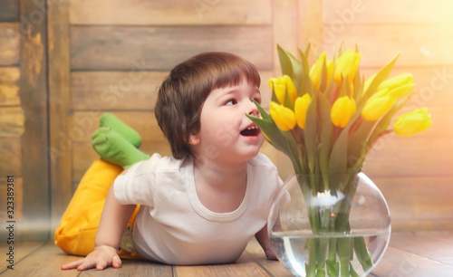 A small child with a bouquet of yellow tulips. A boy with a gift of flowers in a vase. A gift for girls on a female holiday with yellow tulips on the floor.