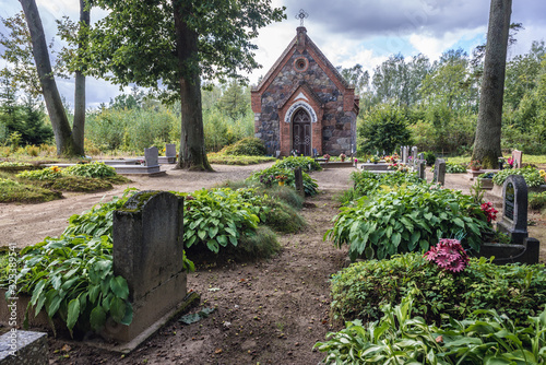 Fototapeta Naklejka Na Ścianę i Meble -  Old graves and stone chapel on a cemetery in Zajaczki, small village near Ostroda town, Poland