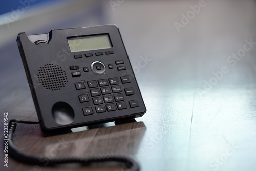 Close Up keypad number Black ip phone is placed on a wooden floor in the office.