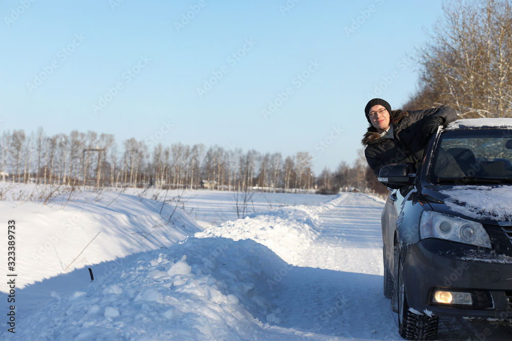 man looks out the car window at the snow-covered road