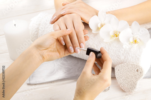 beautiful french manicure with orchid, candle and towel on the white wooden table. manicurist hands