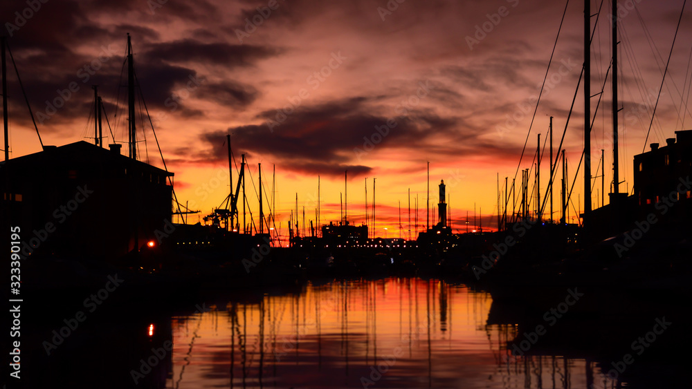 An outstanding sunset at thw harbour of Genoa in Italy with a view of silhouette of landmark Genoa lighthouse 