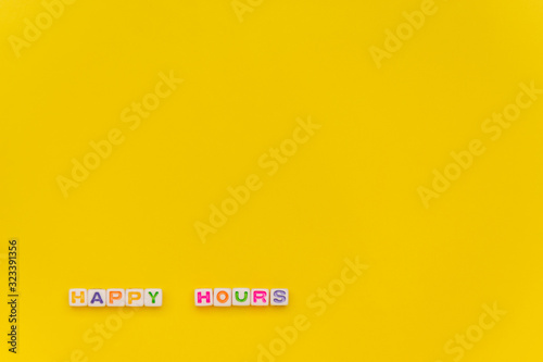 Happy Hours written by white cube with multocolor letters on yellow background