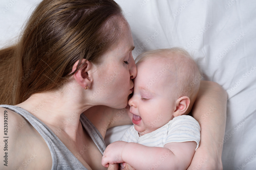 Happy mum holding infant child on hands. Beautiful young mother kissing her baby. Happy mum holding infant child on hands. Beautiful young mother kissing her baby.