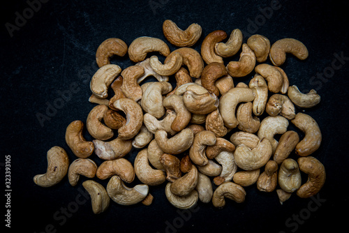 lots of fried cashews nuts scattered on grey background with copy space
