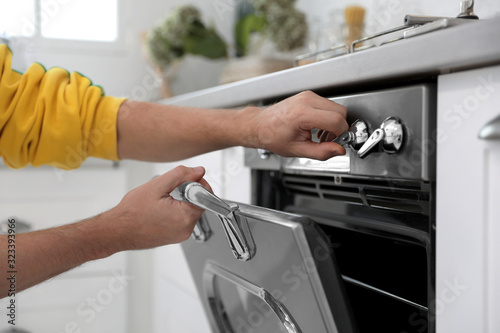 Man using modern oven in kitchen, closeup