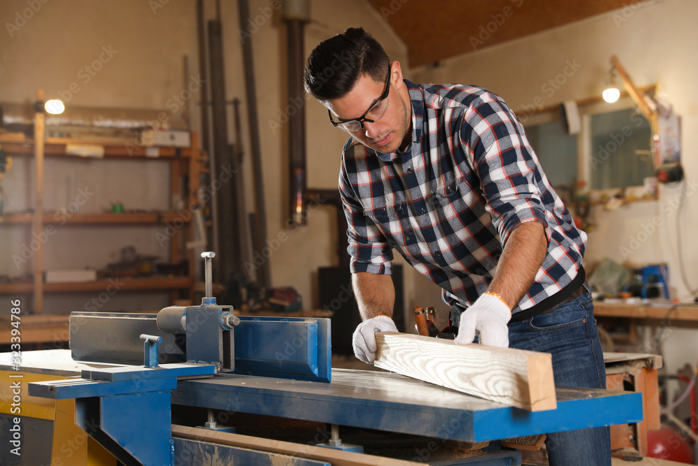 Professional carpenter working with wooden plank in workshop
