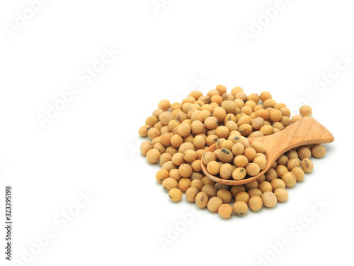 Soybeans in wooden spoon on pile isolated on white background.