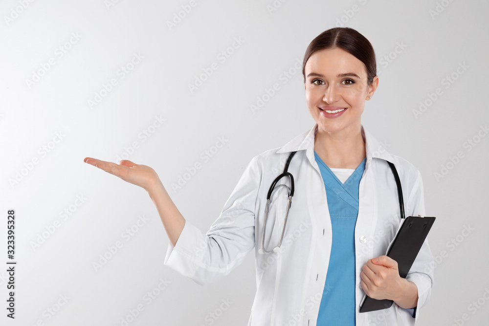 Doctor with stethoscope and clipboard on light grey background Doctor with stethoscope and clipboard on light grey background