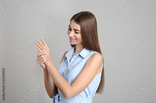 Happy young woman wearing beautiful engagement ring on grey background