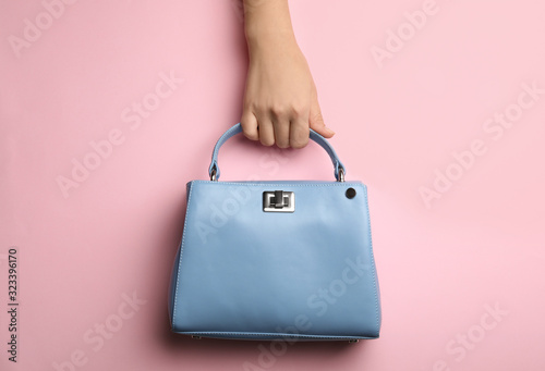 Woman holding small bag on pink background, top view