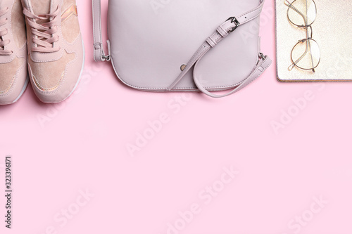 Stylish shoes, small woman's bag, notebook and glasses on pink background, flat lay. Space for text