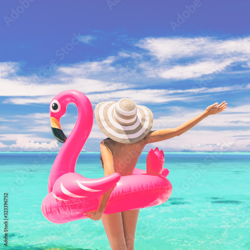 Happy summer vacation fun woman tourist enjoying travel holidays ready for swimming with flamingo float - funny holiday nudist beach concept. photo