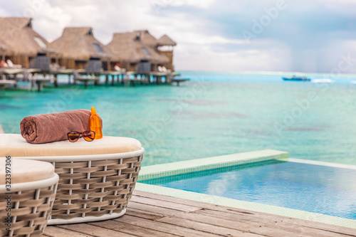 Fototapeta Naklejka Na Ścianę i Meble -  Luxury Bora Bora overwater bungalow villas high end hotel in Tahiti, French Polyneisa. Ocean view summer travel destination resort background, sun lounger with towel , sunscreen and sunglasses.