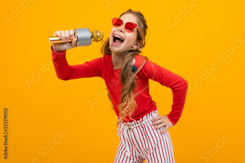 cute european girl singing into a microphone on a yellow background
