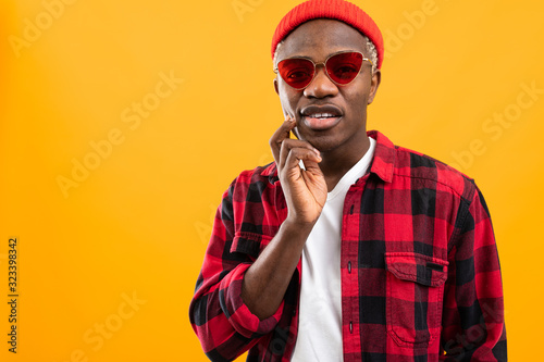 stylish black american guy in red retro glasses on orange background with copy space