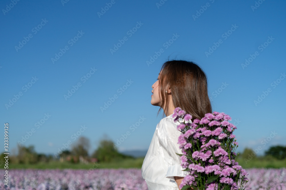 Woman in white dress with white umbrella posing in purple margaret flower field. Woman in white dress with white umbrella posing in purple margaret flower field.