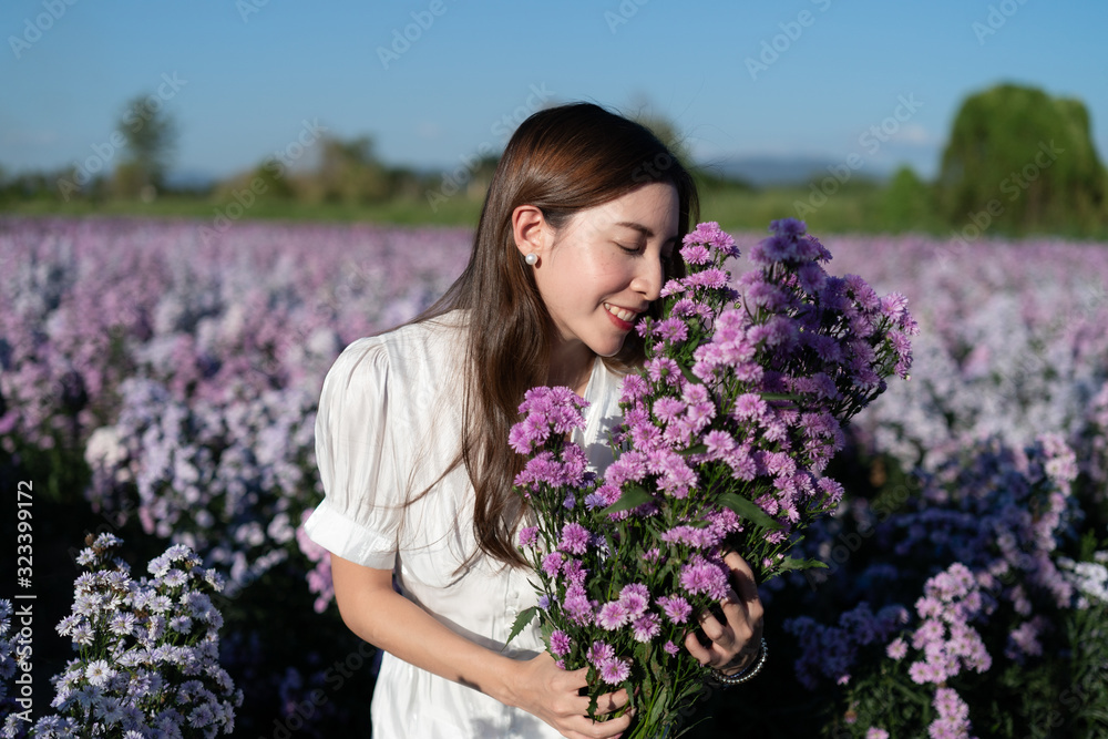 Woman in white dress with white umbrella posing in purple margaret flower field. Woman in white dress with white umbrella posing in purple margaret flower field.