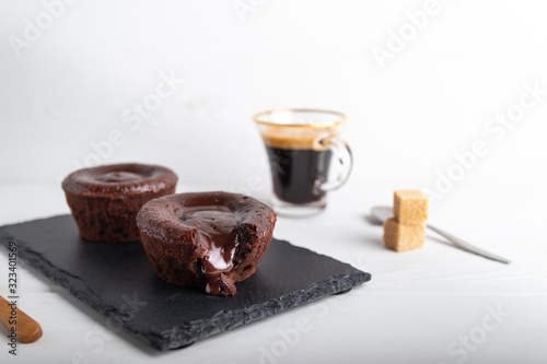 Warm chocolate lava cake on a black plate with a cup of coffee on a white background