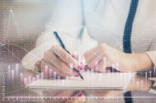 Double exposure of hands making notes with forex chart huds. Stock market concept.