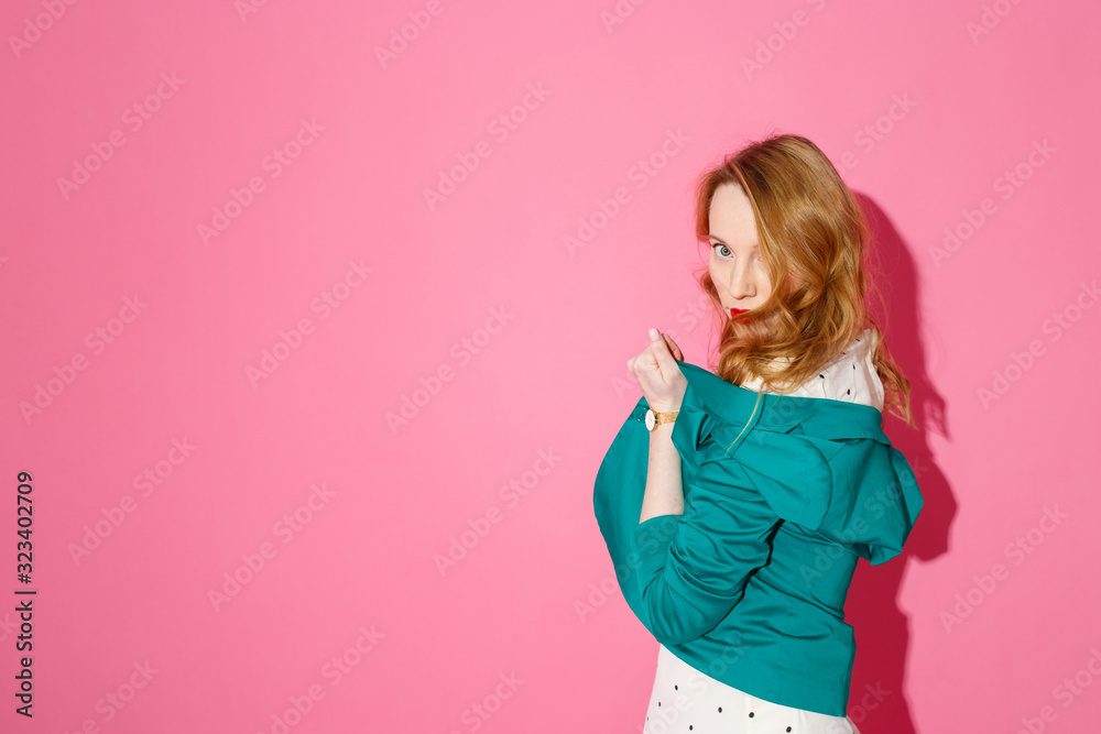 Beautiful fashionable young blonde woman posing in a studio, wide opened green jacket and summer dress. Long wavy hairstyle. Bright pink background. Fashion autumn spring summer photo. Beautiful fashionable young blonde woman posing in a studio, wide opened green jacket and summer dress. Long wavy hairstyle. Bright pink background. Fashion autumn spring summer photo.