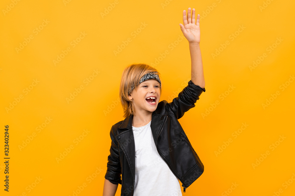 Stylish young boy in black jacket and white t-shirt rejoices