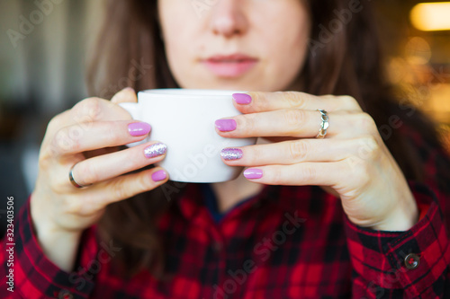 The girl is holding a cup of coffee. Close-up.