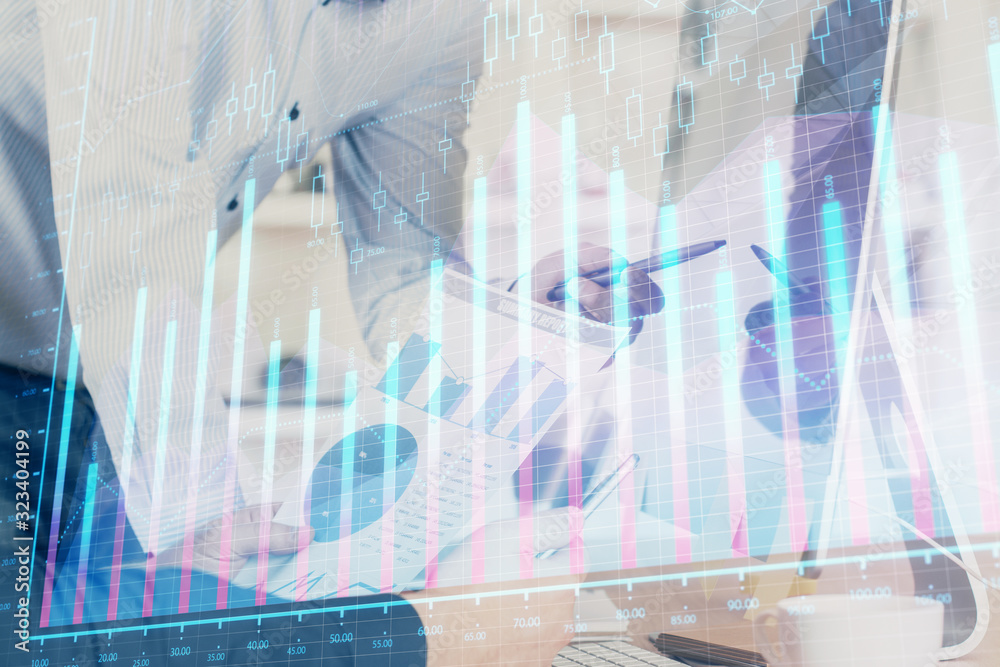 Double exposure of chart with businessman typing on computer in office on background. Concept of hard work.