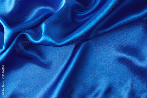 Blue silk background with a folds. Abstract texture of rippled satin surface