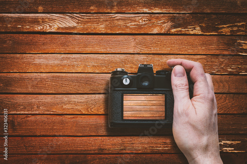 Professional Photographer Taking Picture of Brown Wooden Background Using Retro Mirorless Camera - Finger on Shutter Release - Top View Rear Display with Photo Preview photo