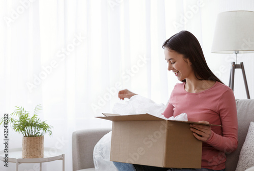 Excited young woman receive long awaited order in cardboard