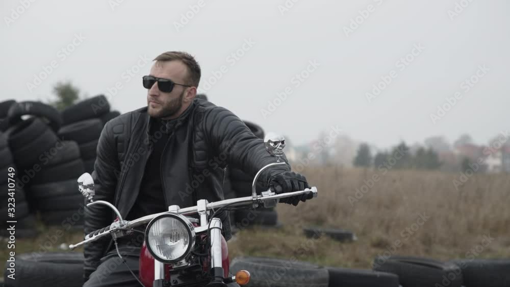 Portrait of motorbiker on motocycle looking at camera near tires Portrait of motorbiker on motocycle looking at camera near tires