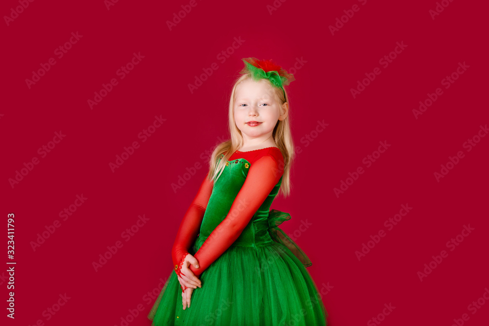 Beautiful little plump girl princess dancing in luxury green dress isolated on red background. Carnival party with costumes