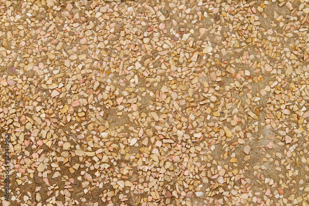 Small chopped pebbles of light shades in the frozen cement. Selective focus. Textured stone background. A wall of gravel and small pebbles Small chopped pebbles of light shades in the frozen cement. Selective focus. Textured stone background. A wall of gravel and small pebbles
