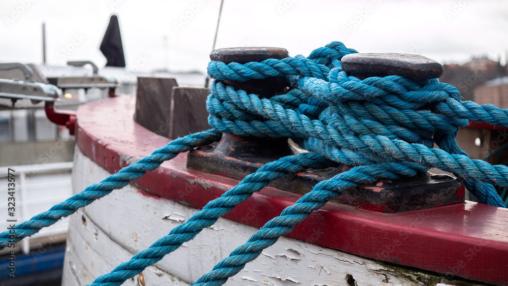 Thick blue boat rope in the foreground, is tied to a dock in boat vessel in Stockholm, Sweden.