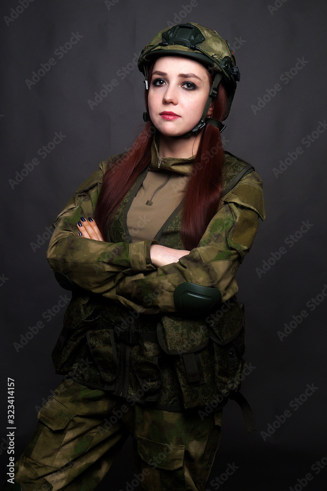 A girl soldier in camouflage clothing poses in a Studio