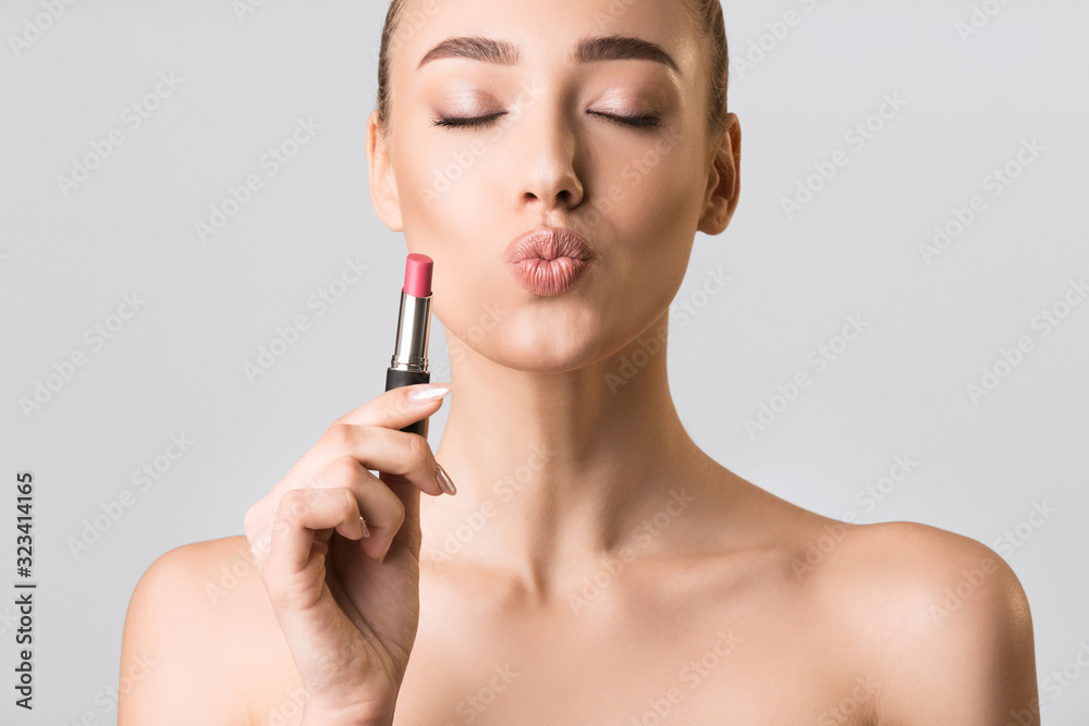 Model Girl Holding Lipstick Posing On Gray Studio Background Model Girl Holding Lipstick Posing On Gray Studio Background