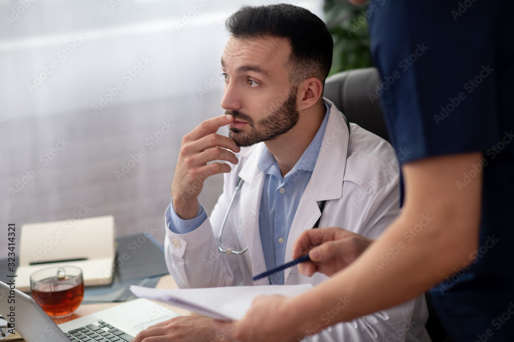 Bearded head doctor in a white robe looking thoughtful Bearded head doctor in a white robe looking thoughtful